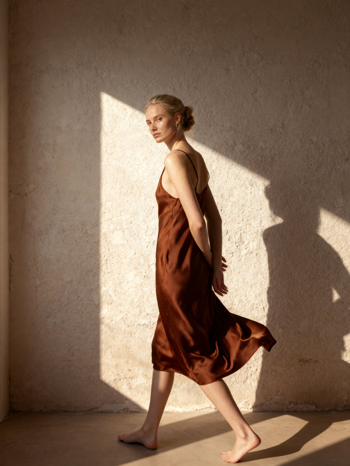 woman walking along a lime washed wall in an ecru blazer and wide leg trousers