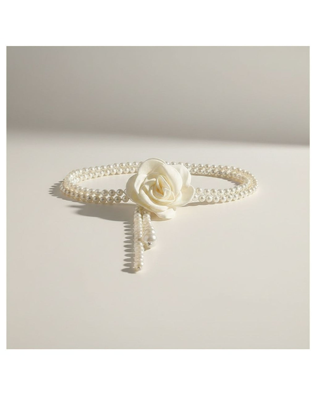the bloom: close view of the fabric rose knot and the loose pearl tail