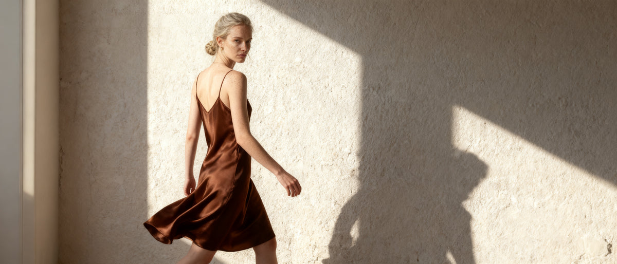 woman walking in an ecru blazer and wide-leg trousers along a lime-washed wall