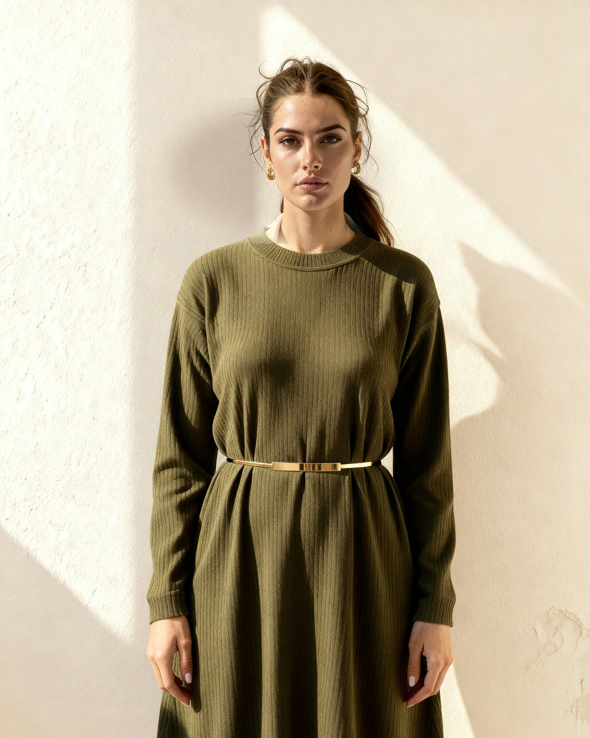 the plate: woman wearing the thin gold metal waist band over an oversized olive knit dress